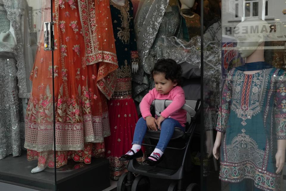 A girl sits on a stroller in the district of Southall in London, Tuesday, Sept. 13, 2022. In a church in a West London district known locally as Little India, a book of condolence for Queen Elizabeth II lies open. Five days after the monarch’s passing, few have signed their names. The congregation of 300 is made up largely of the South Asian diaspora, like the majority of the estimated 70,000 people living in the district of Southall, a community tucked away in London's outer reaches of London and built on waves of migration that span 100 years. (AP Photo/Kin Cheung)