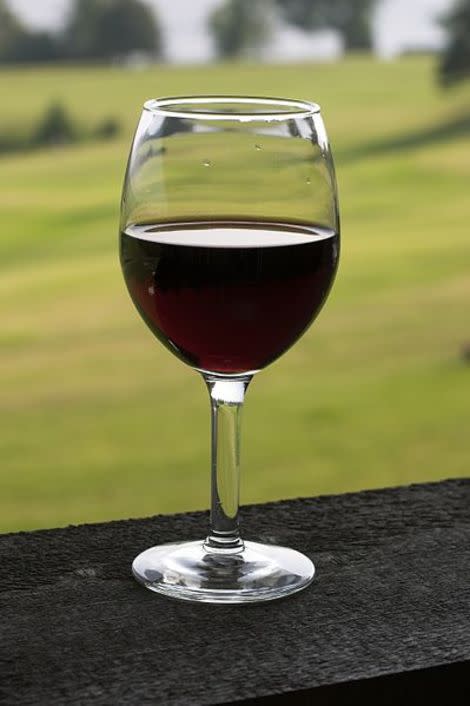 A glass of red wine is seen on a table.