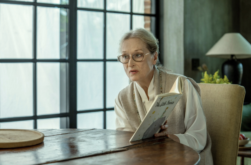 meryl streep's character reading a children's book at a dining table