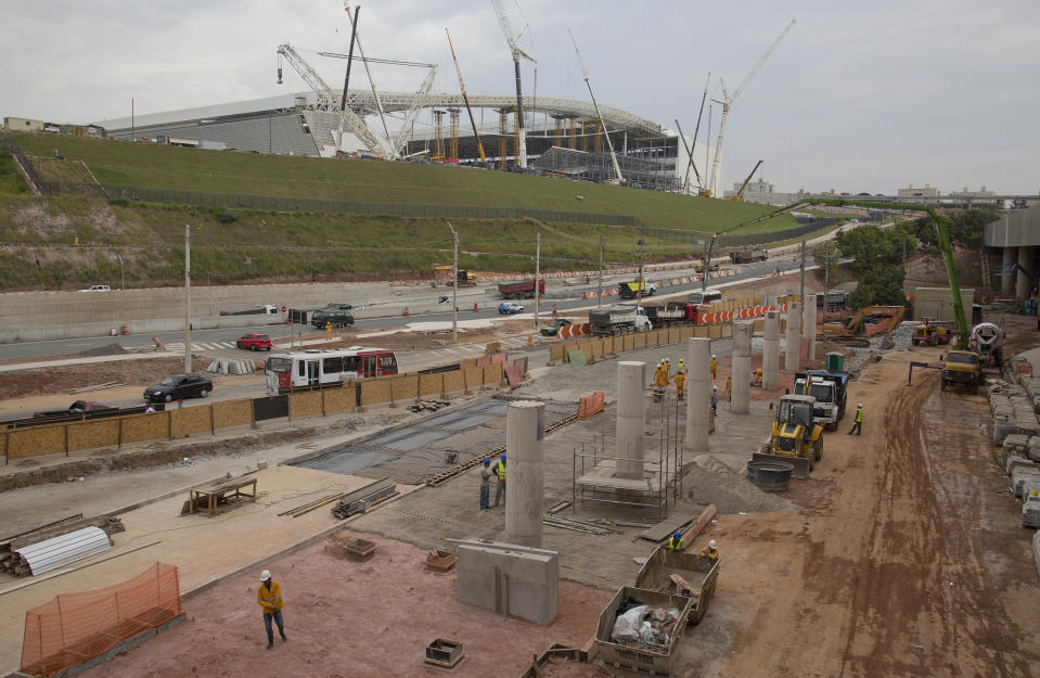 Men work on the construction of a bus terminal near the Itaquerao stadium in Sao Paulo, Brazil, Wednesday, April 9, 2014. Construction continues in and around the stadium that is slated to host the World Cup opener match between Brazil and Croatia on June 12. (AP Photo/Andre Penner)