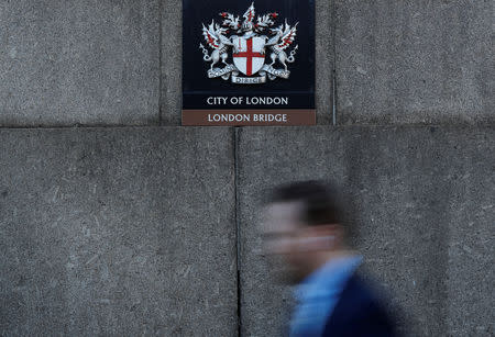 FILE PHOTO: A worker walks across London Bridge near the City of London, Britain, September 21, 2018. REUTERS/Peter Nicholls