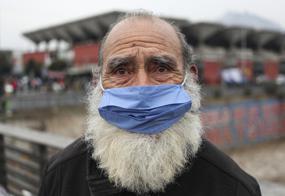 A man wearing a protective face mask as a precaution amid the new coronavirus pandemic, poses for a photo after buying groceries at a market in Santiago, Chile, Monday, June 8, 2020. With Latin America now the epicenter of the pandemic, but with hundreds of millions relying on these markets for food and livelihoods, the debate now centers on whether and how they can operate safely. (AP Photo/Esteban Felix)