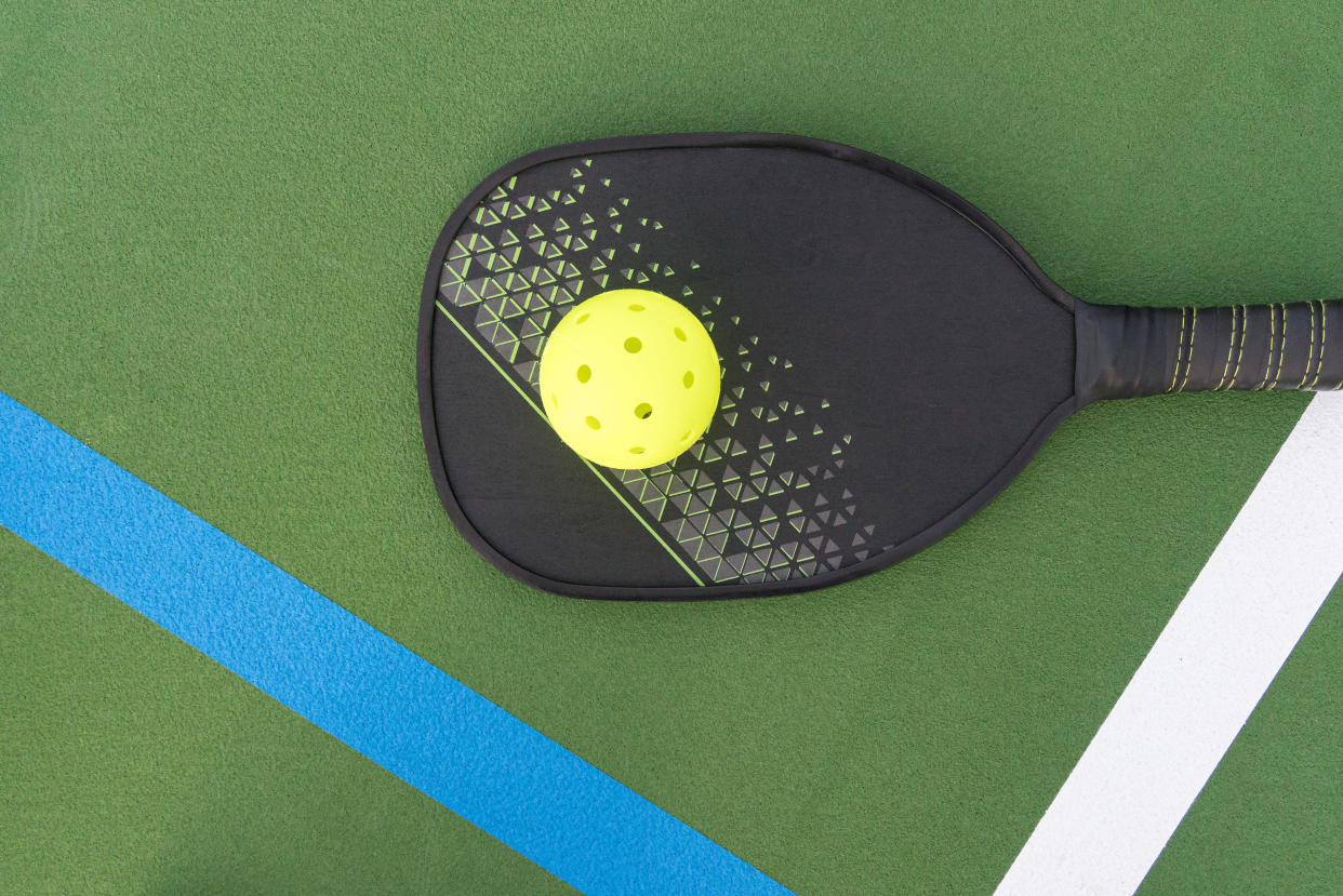 A pickleball paddle and ball on the pickle ball court