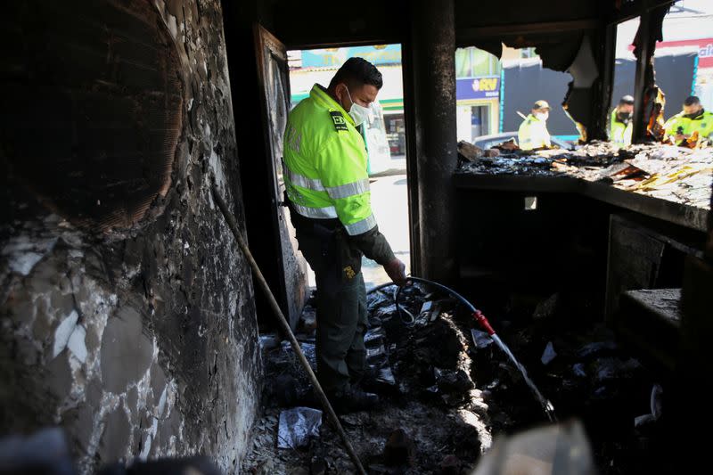 Un policía utiliza una manguera para verter agua en una estación vandalizada durante las protestas contra la brutalidad policial en Bogotá