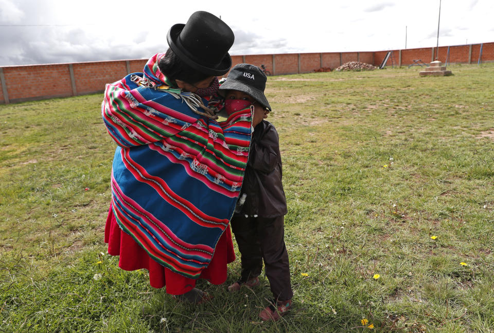 An Aymara Indigenous mother fixes her son's mask before he enters Jancohaqui Tana school, wearing his new protective uniform amid the COVID-19 pandemic during the first week back to school amid the COVID-19 pandemic, near Jesus de Machaca, Bolivia, Thursday, Feb. 4, 2021. (AP Photo/Juan Karita)