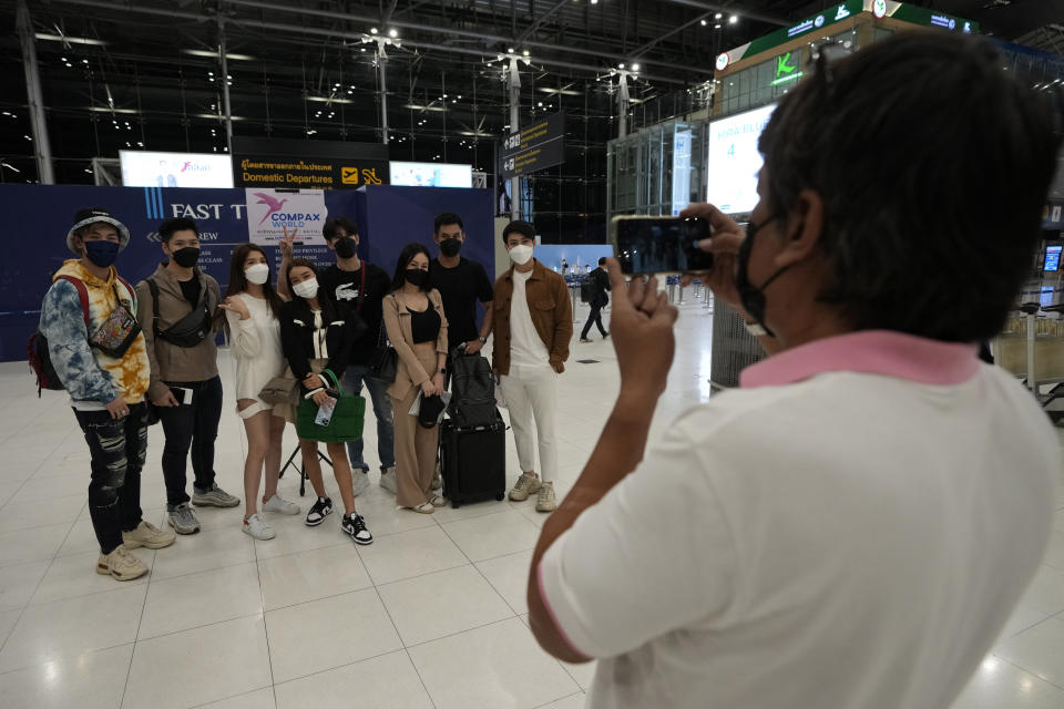 A staff member of a travel agent takes a photo of Thai travelers, from left to right, Sorrasek Thuantawee, Kantpong Madeecharoenporn, Tidarat Margsree, Korranut Nuntanatamon, Tiwasit Ruensorn, Rossarin Chanlekha, Jirawat Jaradwutthikul and Sathaporn Maneephol after check-in for their trip to Osaka and Tokyo, at Suvarnabhumi International Airport in Samut Prakarn province, Thailand, Thursday, June 23, 2022. A group of eight young Thai travelers are excited to return to their favorite tourist destination. Japan is bracing for a return of tourists from abroad, as border controls to curb the spread of coronavirus infections are gradually loosened. Visas are being given only to certain countries, including Thailand and the U.S., that are deemed to pose a minimal health risk, so people can enter without a quarantine. (AP Photo/Sakchai Lalit)