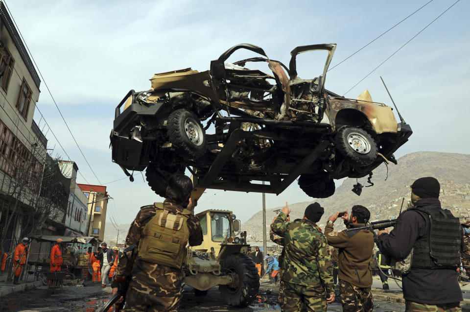 FILE - In this Feb. 1, 2021 file photo, Afghan security personnel remove a damaged vehicle after a bomb attack in Kabul, Afghanistan. Sticky bombs slapped onto cars trapped in Kabul’s chaotic traffic are the newest weapons terrorizing Afghans in the increasingly lawless nation. The surge of bombings comes as Washington searches for a responsible exit from decades of war. (AP Photo/Rahmat Gul, File)