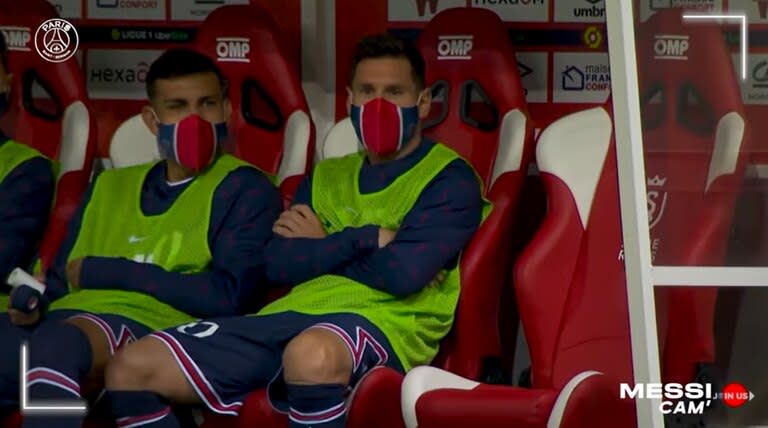 Lionel Messi junto a Leandro Paredes en el banco de suplentes; el 30 saludó tímidamente a quienes lo aclamaban, hinchas de Reims, cuando fue a sentarse allí.