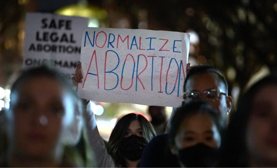 A woman joins others as she holds up a signs supporting abortion rights at a Tuesday evening rally at the RI State House in reaction to the leaked Supreme Court memo hinting a possible overturning of Roe v Wade.