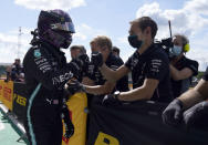 Mercedes driver Lewis Hamilton of Britain, left, celebrates with team members after he clocked the fastest time during the qualifying session for the British Formula One Grand Prix at the Silverstone racetrack, Silverstone, England, Saturday, Aug. 1, 2020. The British Formula One Grand Prix will be held on Sunday. (Will Oliver/Pool via AP)