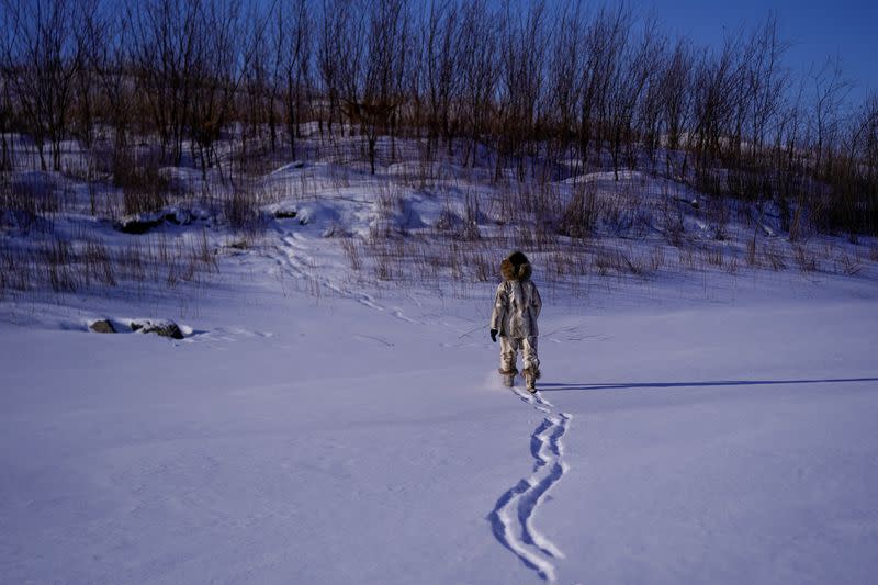 You Wenfeng, 68, an ethnic Hezhen woman, poses with her fishskin clothes at a frozen river in Tongjiang