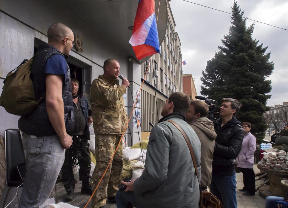 A pro-Russian activist, calling himself Vasily, second left, speaks to other protesters at barricades, with a Russian national flag in front of an entrance to the Ukrainian regional office of the Security Service in Luhansk, 30 kilometers (20 miles) west of the Russian border, in Ukraine, Wednesday, April 9, 2014. Ukrainian Interior Minister Arsen Avakov said the standoff in Luhansk and the two neighboring Russian-leaning regions of Donetsk and Kharkiv must be resolved within the next two days either through negotiations or through the use of force, the Interfax news agency reported. (AP Photo/Igor Golovniov)