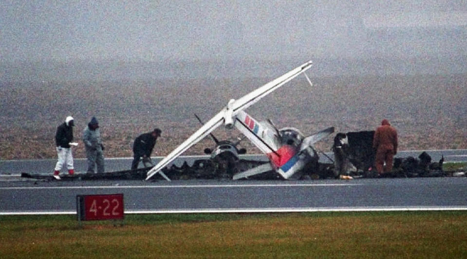 FILE - In this Nov. 21, 1996 file photo, federal aviation officials examine the wreckage of two planes that collided on the runway of Baldwin Municipal Airport in Quincy, Ill., killing all 14 people on both aircraft. Mark Hanna, who became director of the Quincy airport about two years after the crash and before moving to the same job at Springfield's Abraham Lincoln Capital Airport, said if a tower was there, it's highly likely that the accident would have been prevented. Looming federal budget cuts could mean the closure of nearly 240 air traffic control towers across the country, stripping away an extra layer of safety during takeoffs and landings and leaving many pilots to manage the most critical stages of flight on their own. (AP Photo/Seth Perlman, File)