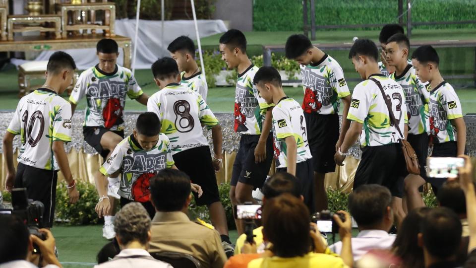 Die Jungen der geretteten Fußballmannschaft dribbeln mit ihrem Trainer auf einem Mini-Fußballplatz. Foto: Vincent Thian/AP