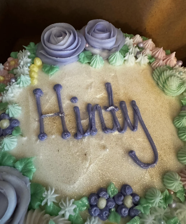 Decorated cake with "Hindy" written on it, surrounded by icing flowers and pearls