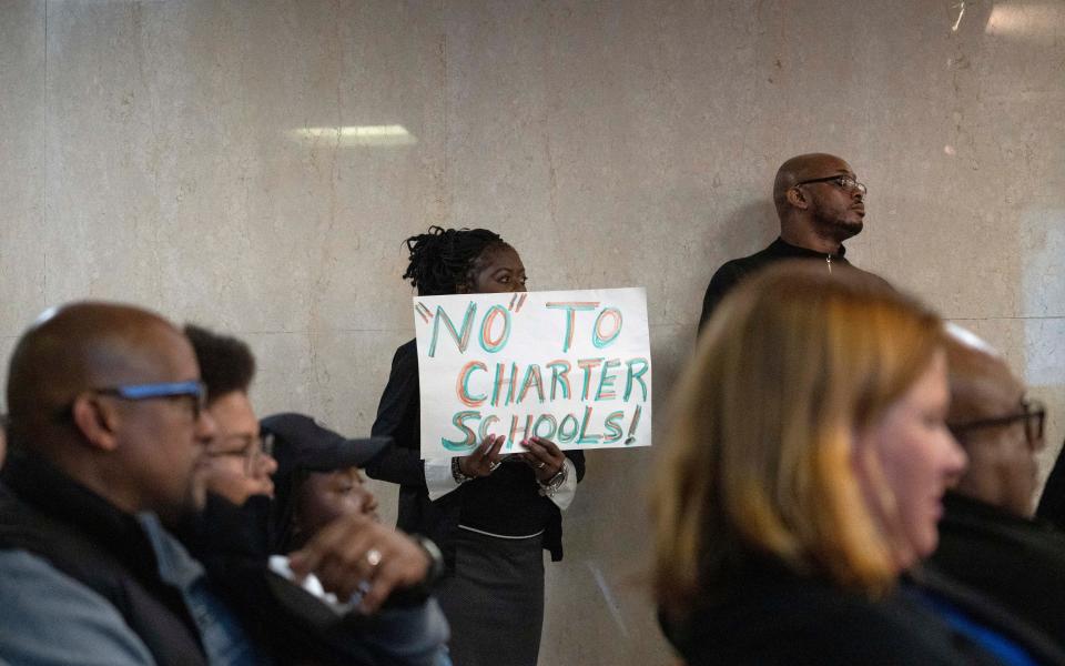Pike Township Trustee Annette Johnson stands and listens with her sign opposing the charter schools during a replication meeting concerning a vote approve two new charter high schools in Pike Township Tuesday, Nov. 15, 2022, at the City Council Building in Indianapolis. 