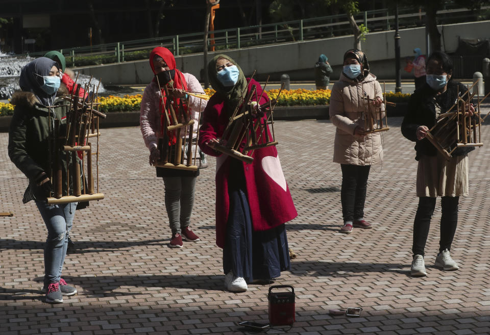 Indonesian migrant workers wear face masks as they play the traditional music instrument "angklung" in Hong Kong, Monday, Jan. 27, 2020. Hong Kong announced it would bar entry to visitors from the mainland province at the center of the outbreak. Travel agencies were ordered to cancel group tours nationwide following a warning the virus's ability to spread was increasing. (AP Photo/Achmad Ibrahim)