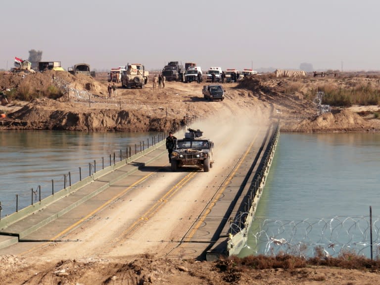 Iraqi pro-government forces cross a bridge over the Euphrates as they head towards Ramadi