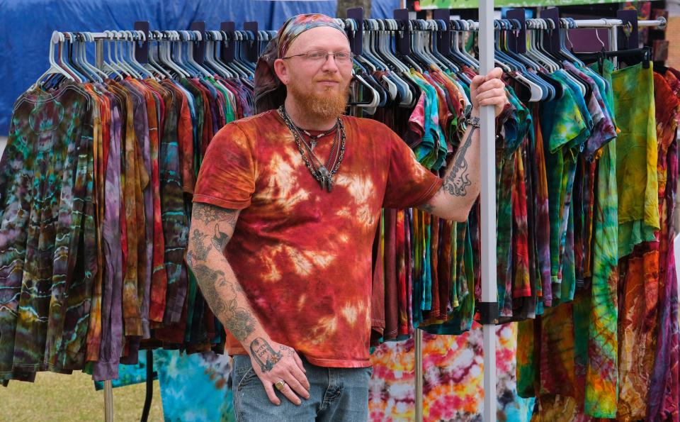 Tie dye artist Charles Cook stands with his merchandise at the Druid City Arts Festival in Government Plaza on March 31, 2023.