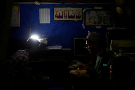 Men eat their lunch at a printing press shop during a power outage in Karachi, Pakistan April 12, 2018. REUTERS/Akhtar Soomro/Files