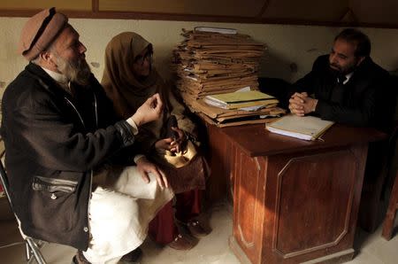 Muhammad Azeem (L) and Sajida Parveen, the parents of Ehsan Azeem, who was sentenced to death by a military court, talk to their lawyer at his office in Rawalpindi January 23, 2015. REUTERS/Faisal Mahmood