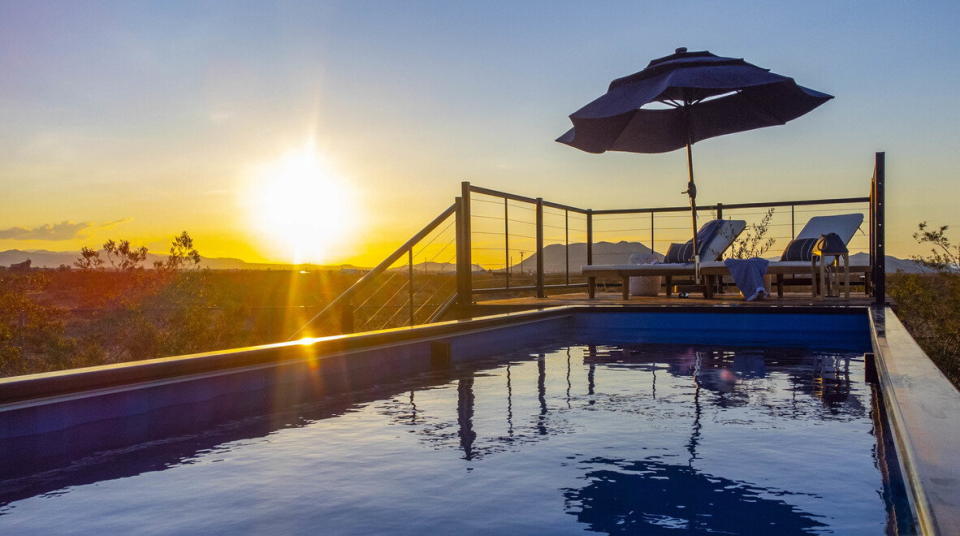 The sun shines across the face of the shipping container pool as it sinks into the distant horizon.