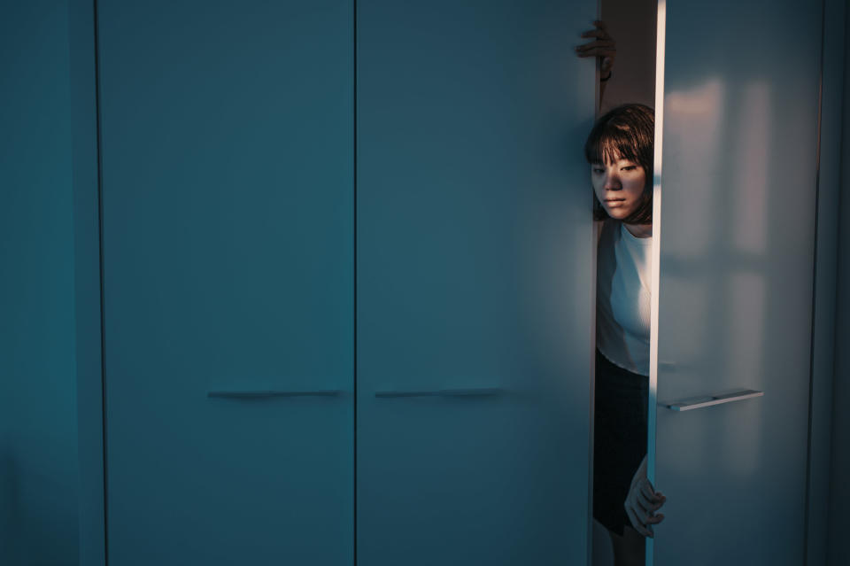 young woman cautiously coming out from behind a door