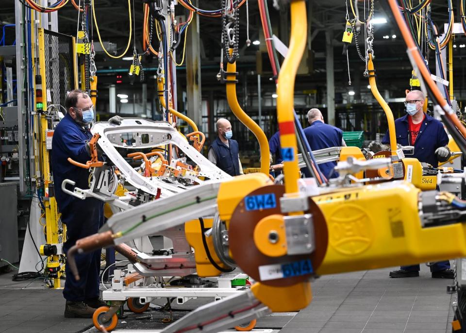 GM workers use human assistance automation on vehicle doors at the General Motors assembly plant during the COVID-19 pandemic in Oshawa, Ont., on Friday, March 19, 2021. 
