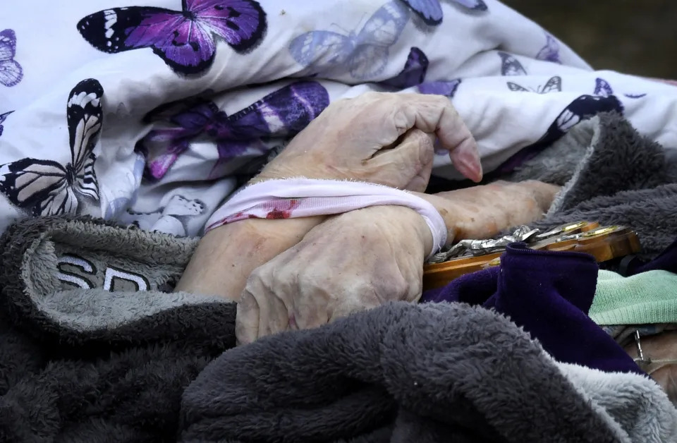 The body of a woman holding a cross and covered in butterfly-print sheets is recovered in Bucha. 