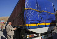 In this Oct. 31, 2018 photo, a Lebanese customs officer stamps a truck waiting to cross into Syria from the Lebanese border crossing point of al-Masnaa, in Bekaa Valley, Lebanon. The long-awaited reopening of a vital border crossing between Syria and Jordan earlier this month was supposed to bring relief to Lebanese farmers and traders looking to resume exports to Gulf countries. But the commerce has so far been complicated by politics, high transit fees and fighting over which trucks pass through which country. (AP Photo/Hussein Malla)