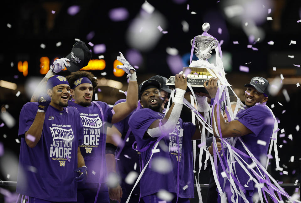 Michael Penix Jr. #9 of the Washington Huskies and Edefuan Ulofoshio #5 celebrate with the trophy after a 37-31 victory against the Texas Longhorns in the CFP Semifinal Allstate Sugar Bowl at Caesars Superdome on January 01, 2024 in New Orleans, Louisiana.