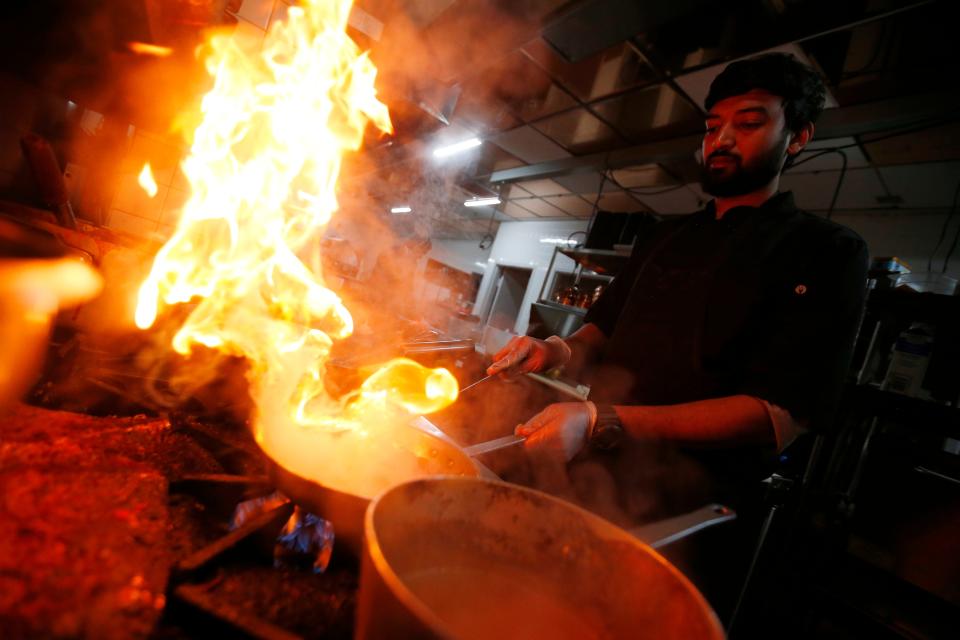 Ritesh Vaze sends flames into the air as he prepares various dressings in the kitchen of the newly opened Saffron by the Sea in Fairhaven.