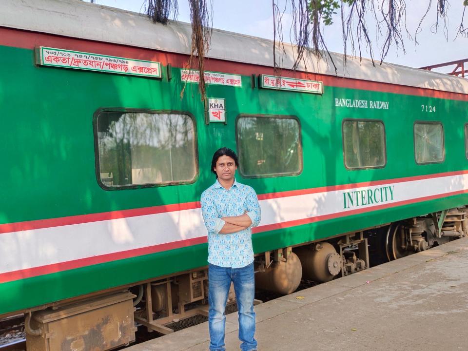 man standing in front of a train at a platform in Bangladesh
