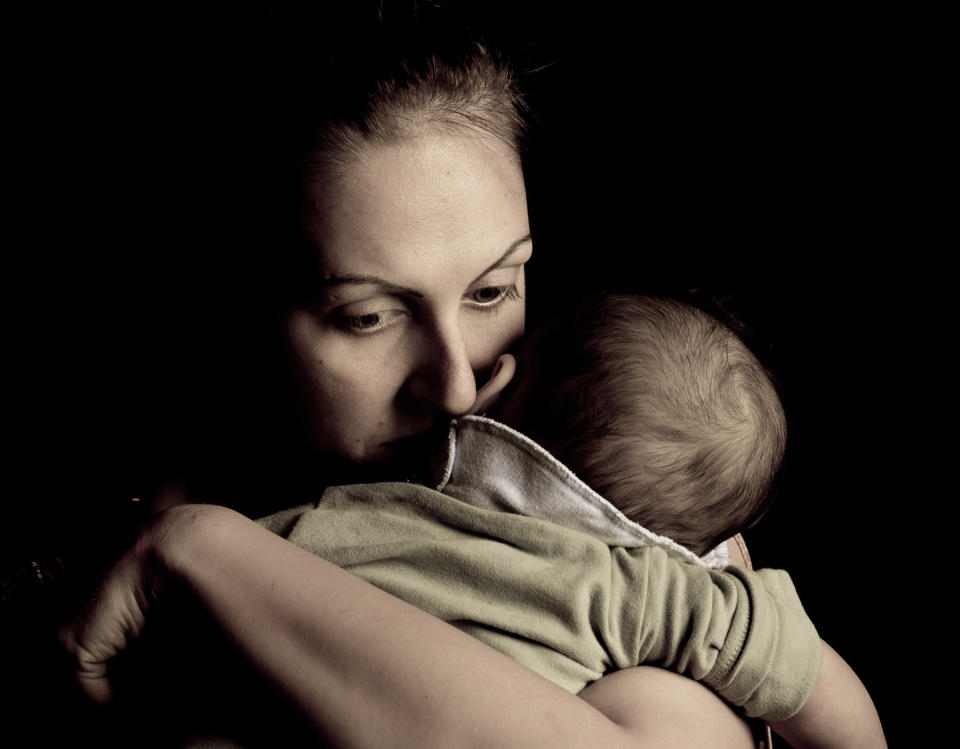 Mother holding baby looking distressed. Posed by model. (Getty Images)