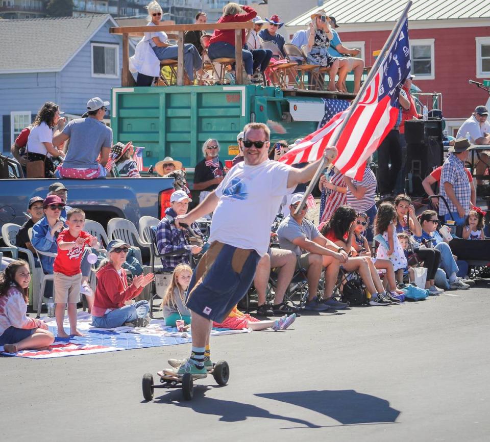 Kelly Lewis rides his skateboard with an American flag at the Fourth of July parade in Cayucos on Monday, July, 5, 2022.