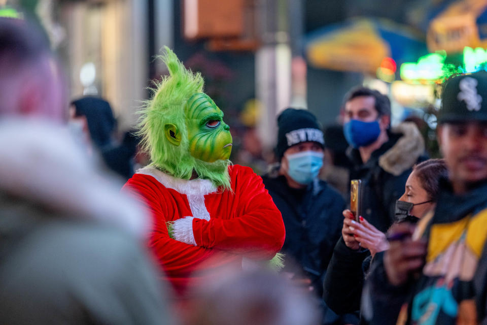 NEW YORK, NEW YORK - DECEMBER 25: A street performer dressed as Dr. Seuss' the Grinch takes photos with tourists in Times Square on December 25, 2021 in New York City. (Photo by Roy Rochlin/Getty Images)