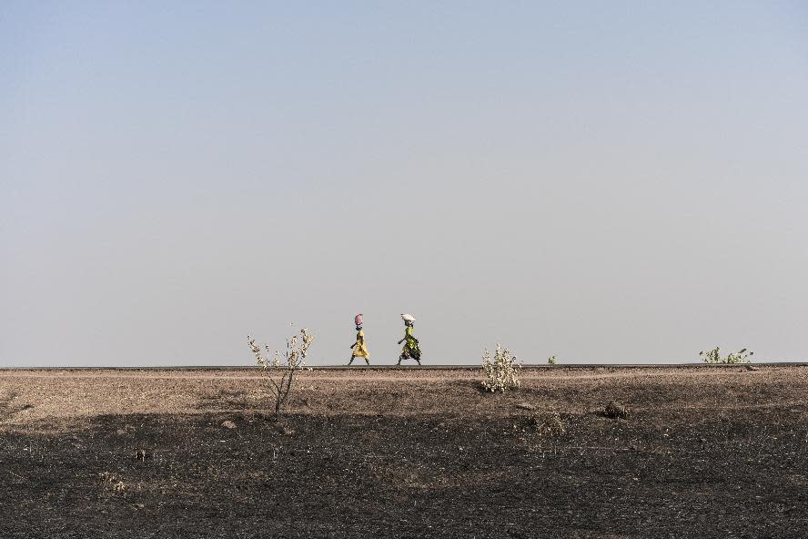 In this photo taken Saturday, March 11, 2017, women walk along the road past parched and burned agricultural land in Aweil, in South Sudan. As World Water Day approaches on March 22, more than 5 million people in South Sudan, do not have access to safe, clean water, compounding the problems of famine and civil war, according to the UNICEF. (Mackenzie Knowles-Coursin/UNICEF via AP)