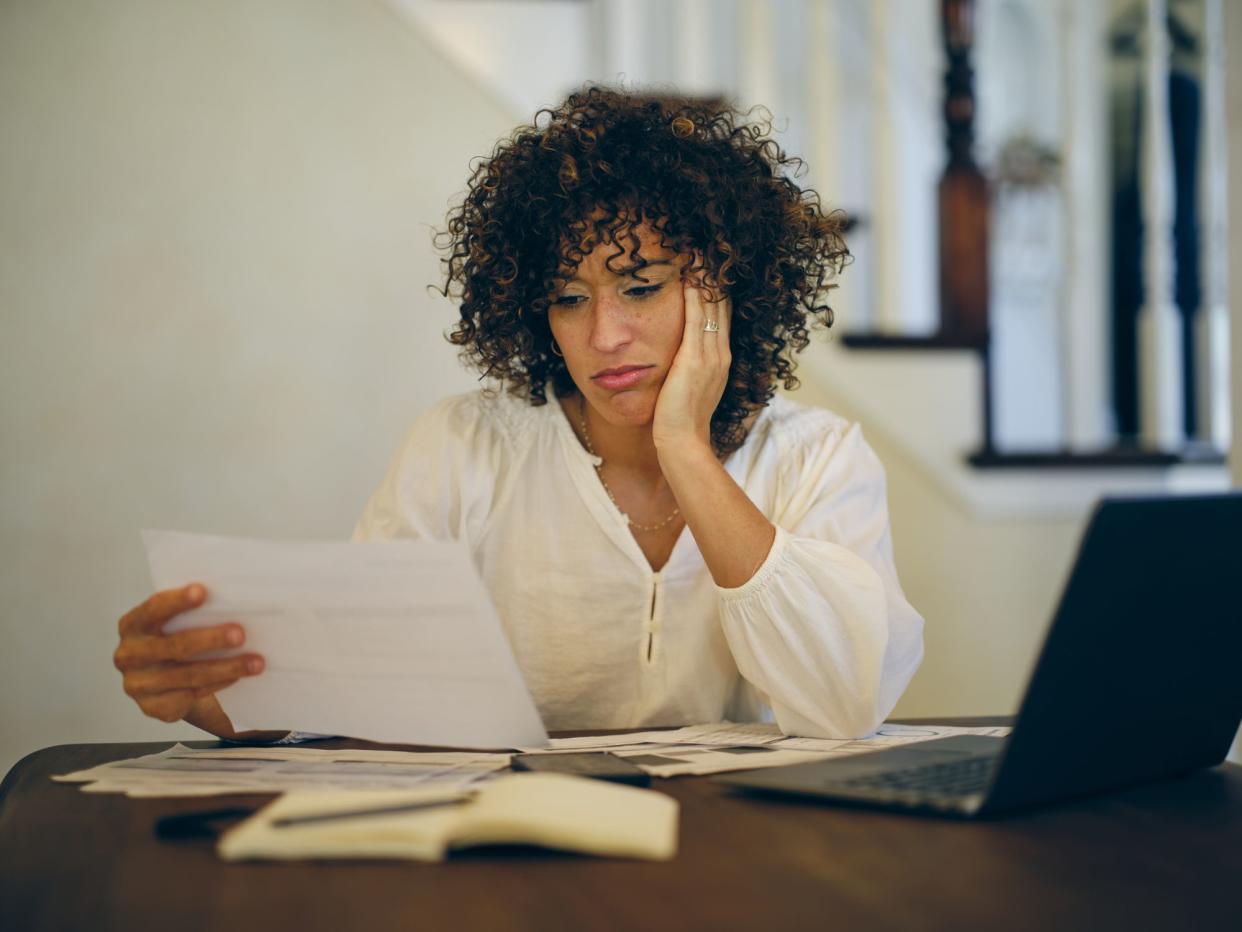 A woman sitting at a table in her home, working on her family finances.