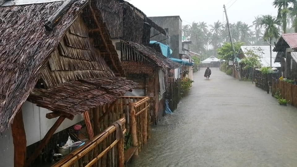 In this photo provided by the San Policarpo Firestation, a man wades through floodwater caused by Typhoon Surigae in the municipality of San Policarpo, Eastern Samar, eastern Philippines on Sunday April 18, 2021. An approaching typhoon has left at least one person dead, another missing and prompted the evacuation of more than 100,000 people as a precaution in the eastern and central Philippines, although the unusual summer storm is not expected to blow into land, officials said Monday. (FO1 Marianne Jabinal/ San Policarpo Firestation via AP)