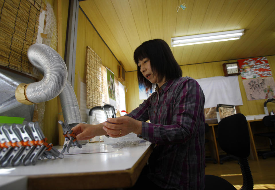 In this Monday, March 3, 2014 photo, Shiho Hironai, 53, makes fishing lures at a workshop in Tanohata, Iwate Prefecture, northeastern Japan. “It's cold, so very cold,” Hironai says of the hut that has served as home for three years. “And the roof is caving in. It has been all along.” (AP Photo/Junji Kurokawa)