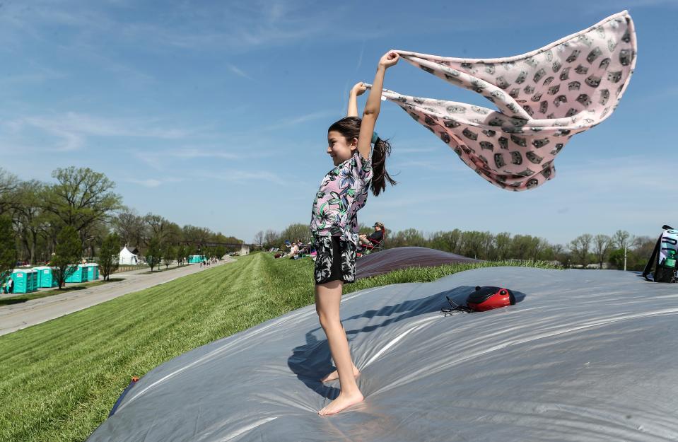 The wind blows the blanket of Kailey Walker of New Salisbury, Ind. after she and her family secured a good viewing spot on the flood wall in Clarksville while they wait before the 2022 Thunder Over Louisville event.  April 23, 2022