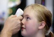 FILE - In this May 19, 2020, file photo, Kaiden Melton, 12, has her temperature taken during a daycare summer camp at Legendary Blackbelt Academy in Richardson, Texas. Coronavirus cases are rising in nearly half the U.S. states, as states are rolling back lockdowns. (AP Photo/LM Otero, File)