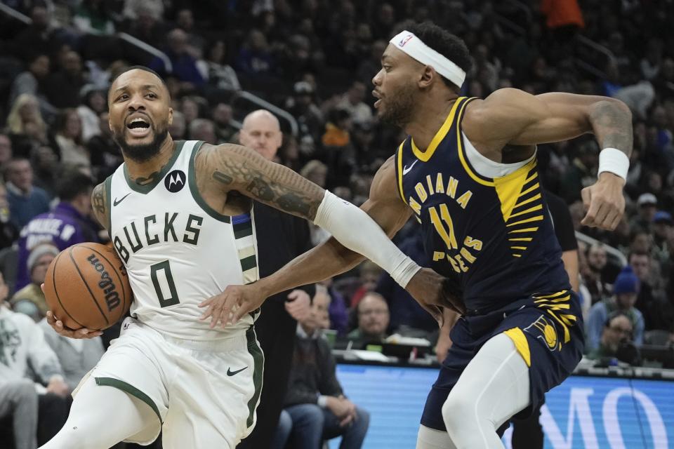 Milwaukee Bucks' Damian Lillard drives by Indiana Pacers' Bruce Brown during the first half of an NBA basketball game Wednesday, Dec. 13, 2023, in Milwaukee. (AP Photo/Morry Gash)