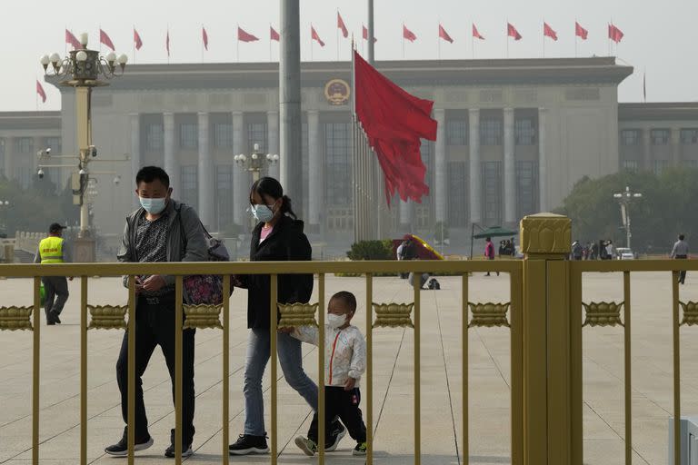 Visitantes con barbijo caminan en la Plaza Tiananmen previo al Congreso del PCC