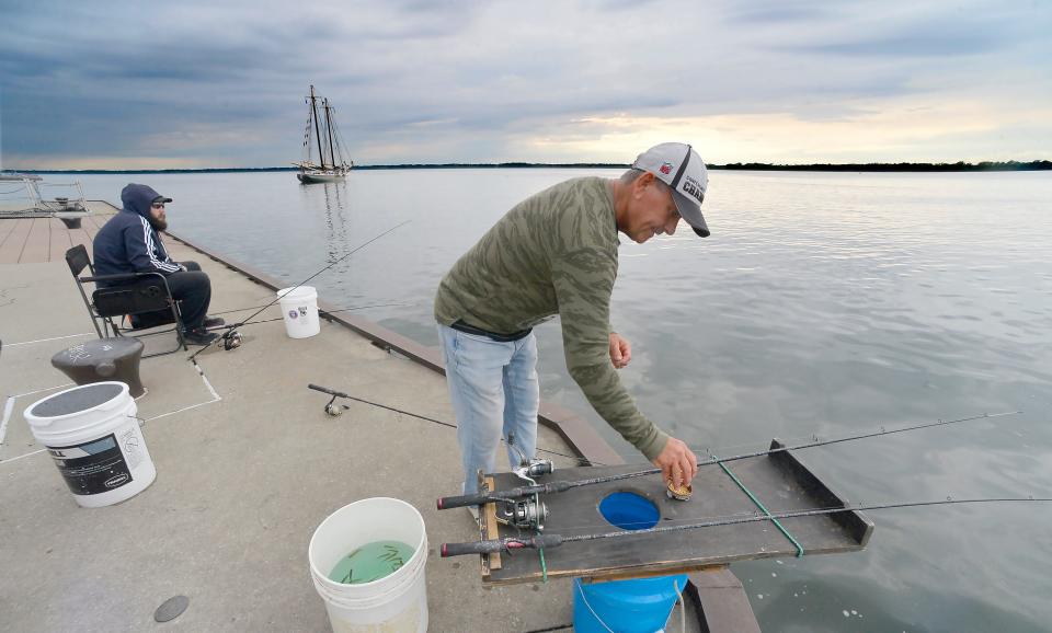 Gary Lyons, 56, of North East, fishes from Dobbins Landing at Presque Isle Bay in Erie on May 28. Lyons, with his great-nephew David Lyons, 29, background, of Erie, said he prefers to fish from the northeast corner of the public dock because "that's where the larger fish like to hang out."