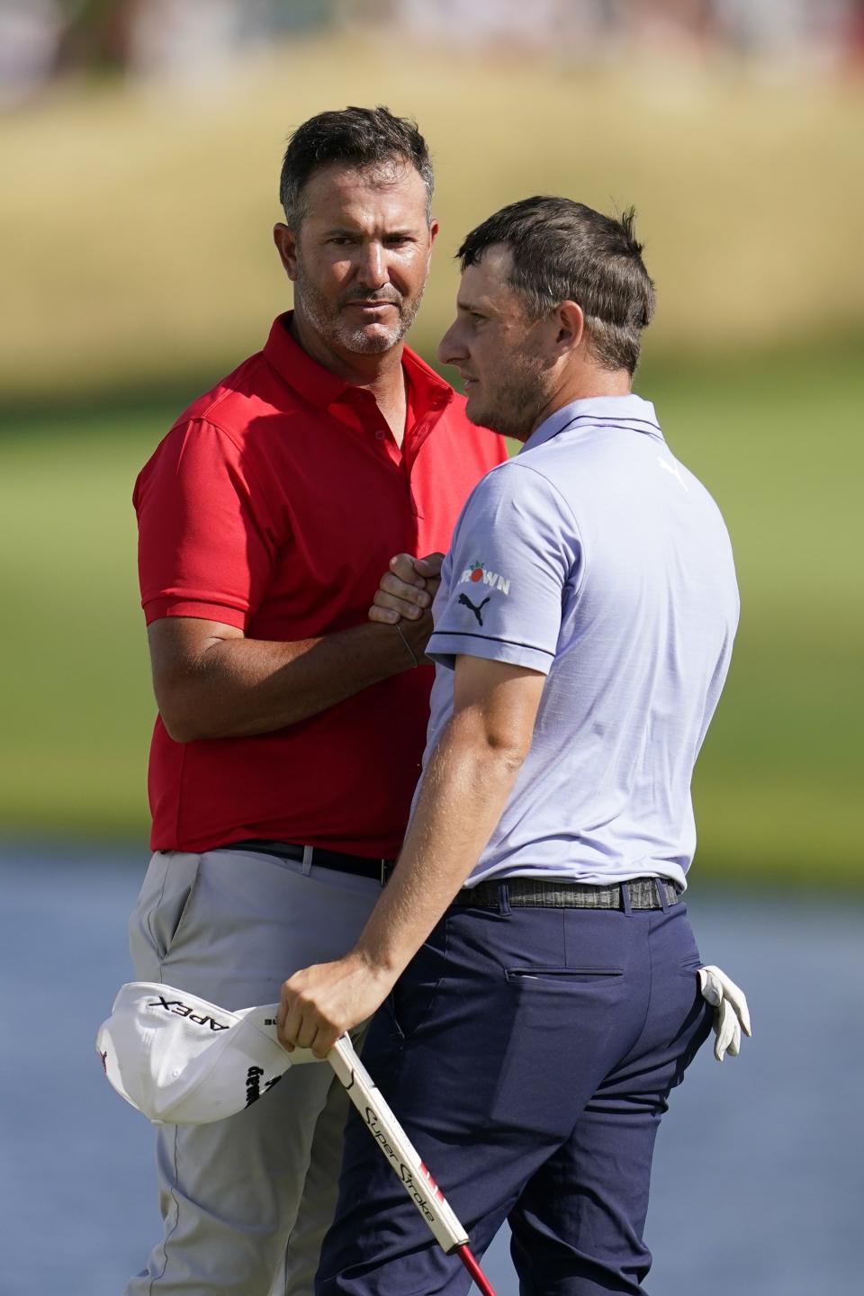 Scott Piercy, left, and Emiliano Grillo, right, of Argentina, shakes hands after finishing play in the final round of the 3M Open golf tournament at the Tournament Players Club in Blaine, Minn., Sunday, July 24, 2022. (AP Photo/Abbie Parr)