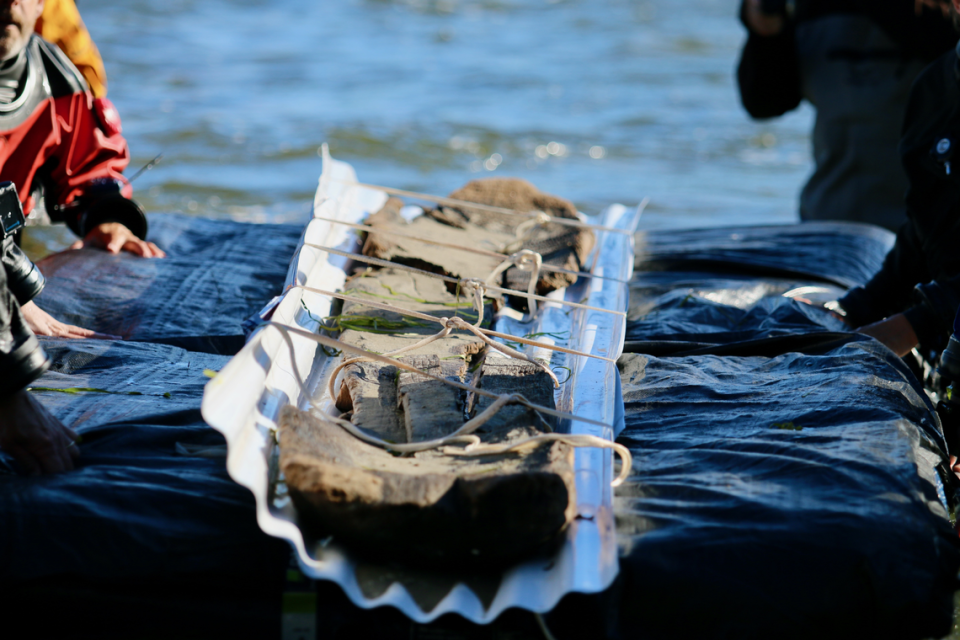 Divers brought the canoe to the surface then floated it toward the crowd waiting on shore.