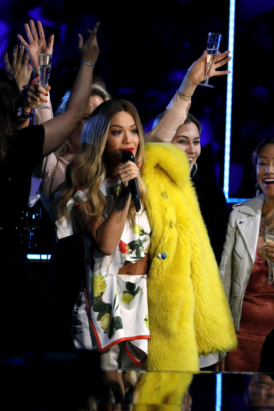 Rita Ora draping a yellow coat over her shoulder