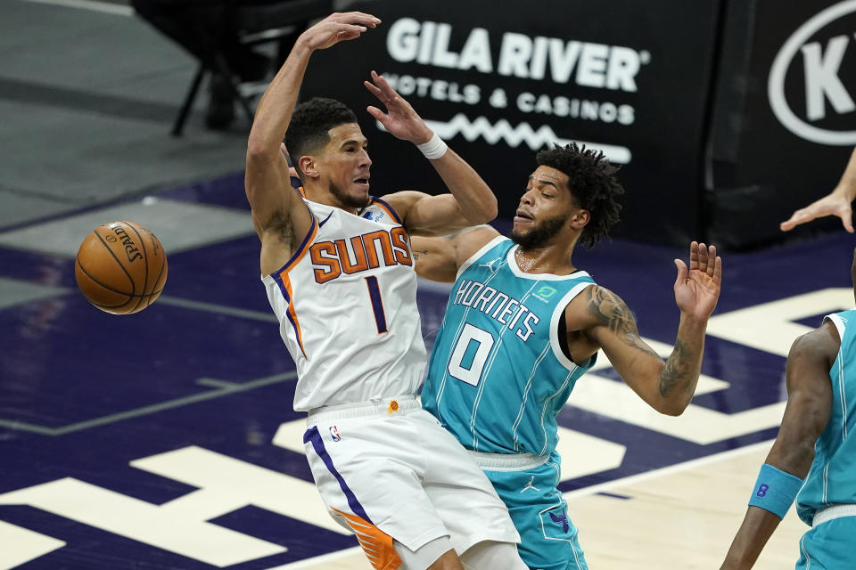 Charlotte Hornets forward Miles Bridges (0) knocks the ball loose from Phoenix Suns guard Devin Booker (1) during the first half of an NBA basketball game, Wednesday, Feb. 24, 2021, in Phoenix. (AP Photo/Matt York)