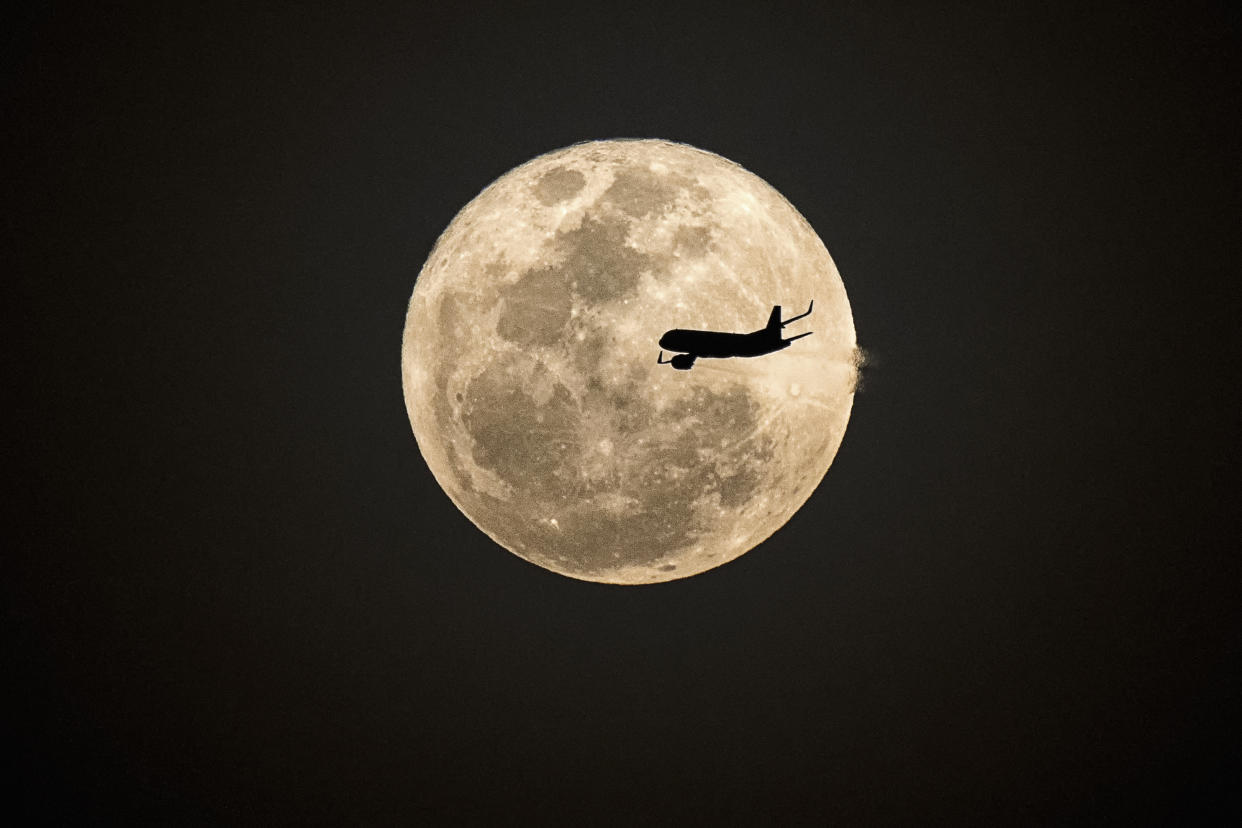 Silhouette aircraft fly in front of supermoon